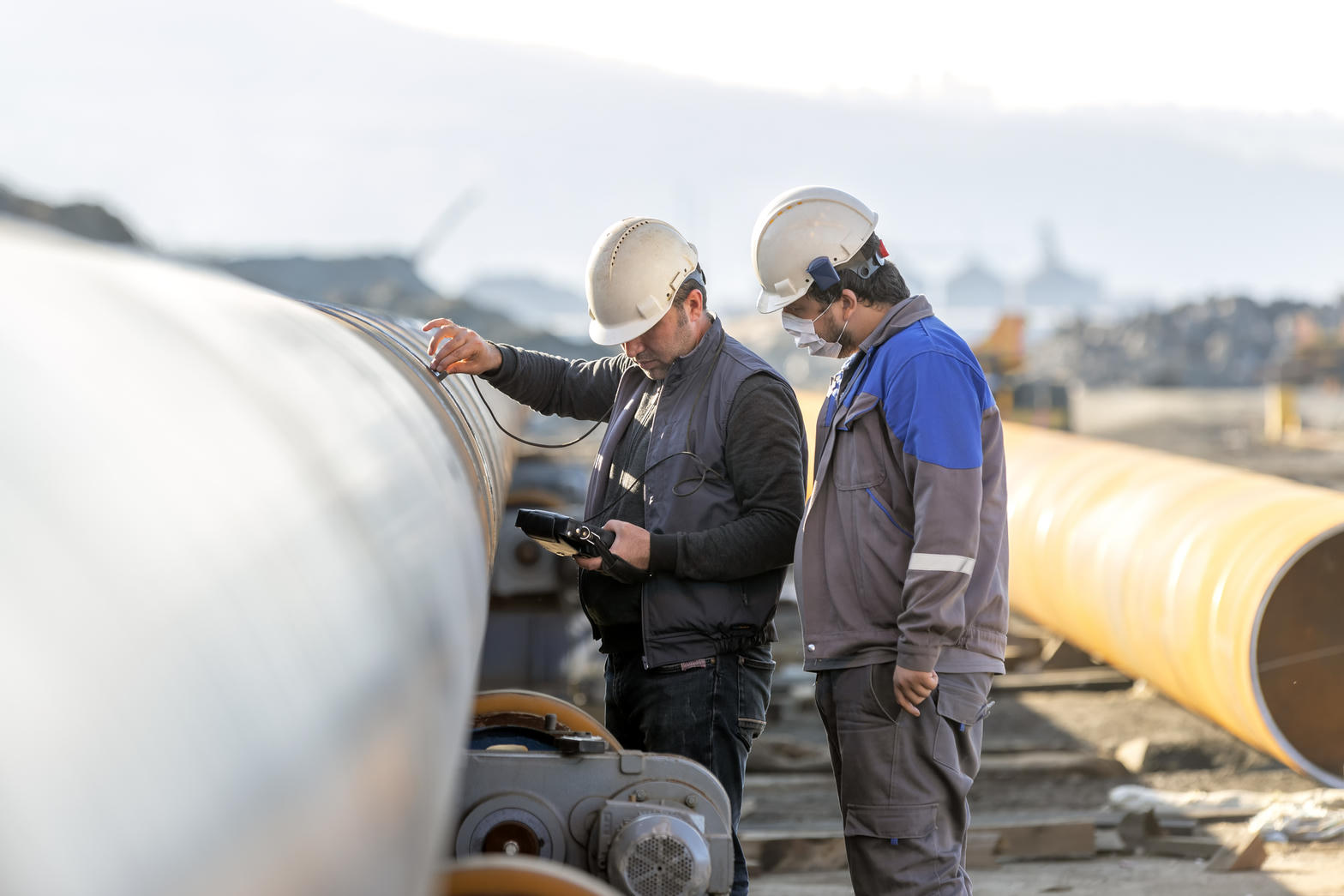 Technicians in hard hats inspecting pipeline in the field